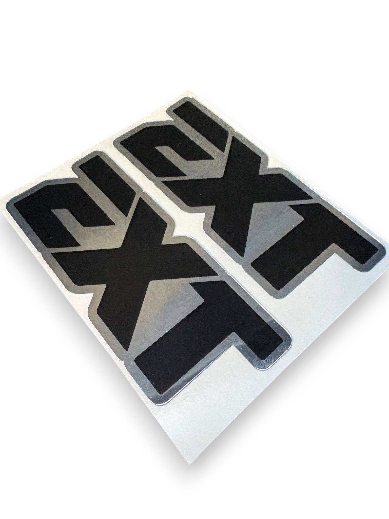 Two black and silver 'EXT' vinyl decals on a white backing sheet, photographed at an angle on a white background.