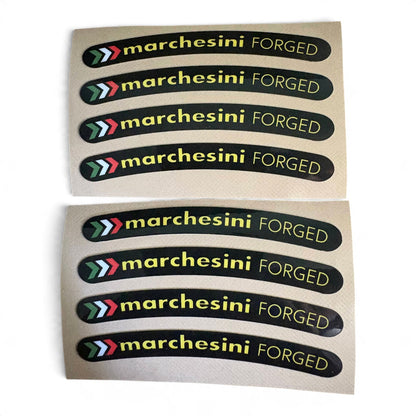 Two sheets of curved black stickers with the text 'marchesini FORGED' in yellow, each sheet containing five stickers. The stickers feature a multi-color chevron logo on the left.